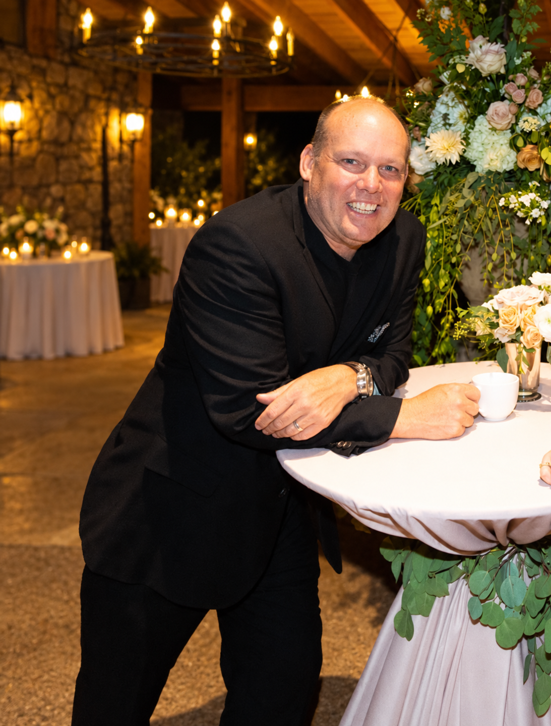 Robert Evans smiling and leaning on a flower-lined reception table at The Broadmoor