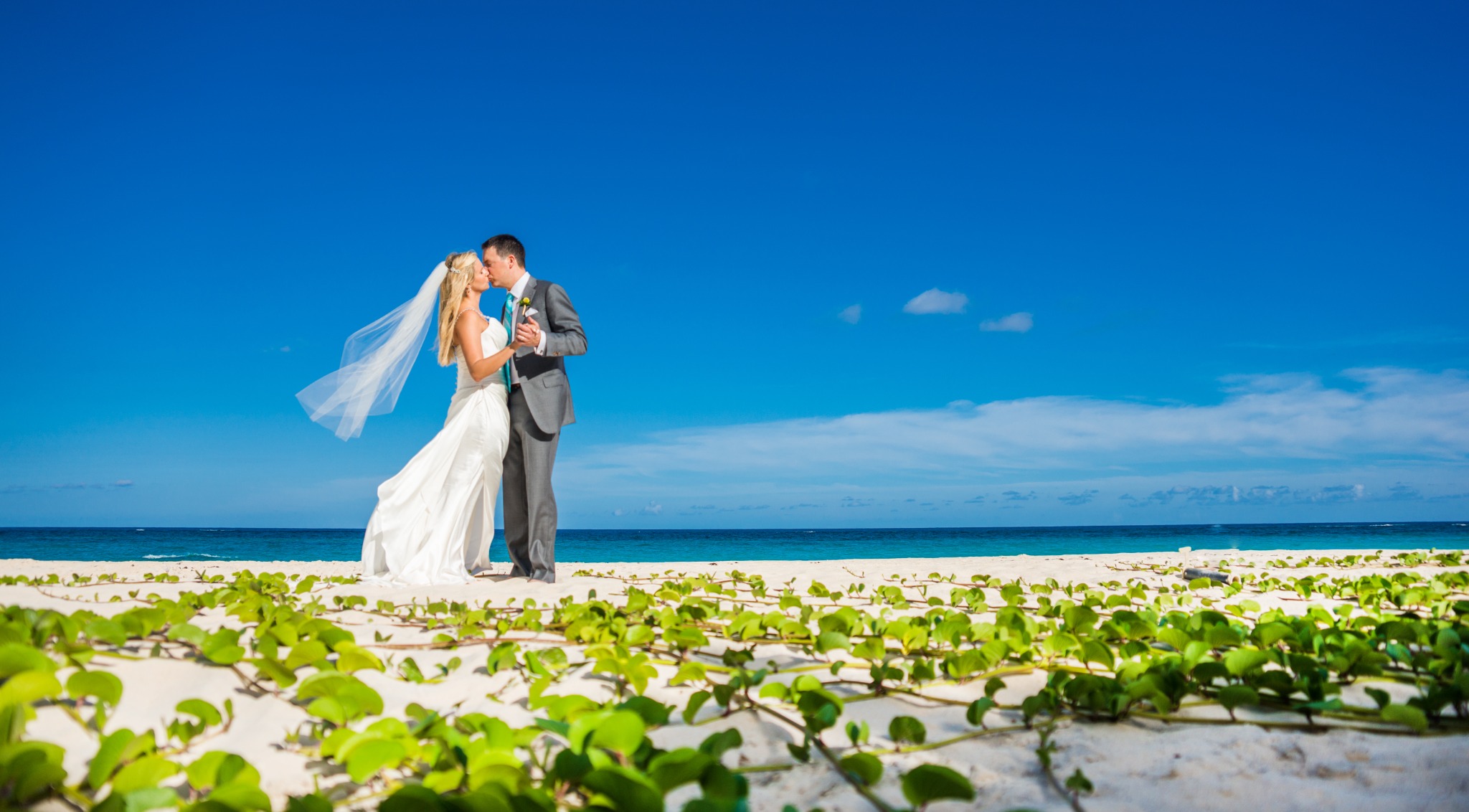 Newlyweds embracing on a bright tropical beach during their destination wedding Newlyweds embracing on a bright tropical beach during their destination wedding