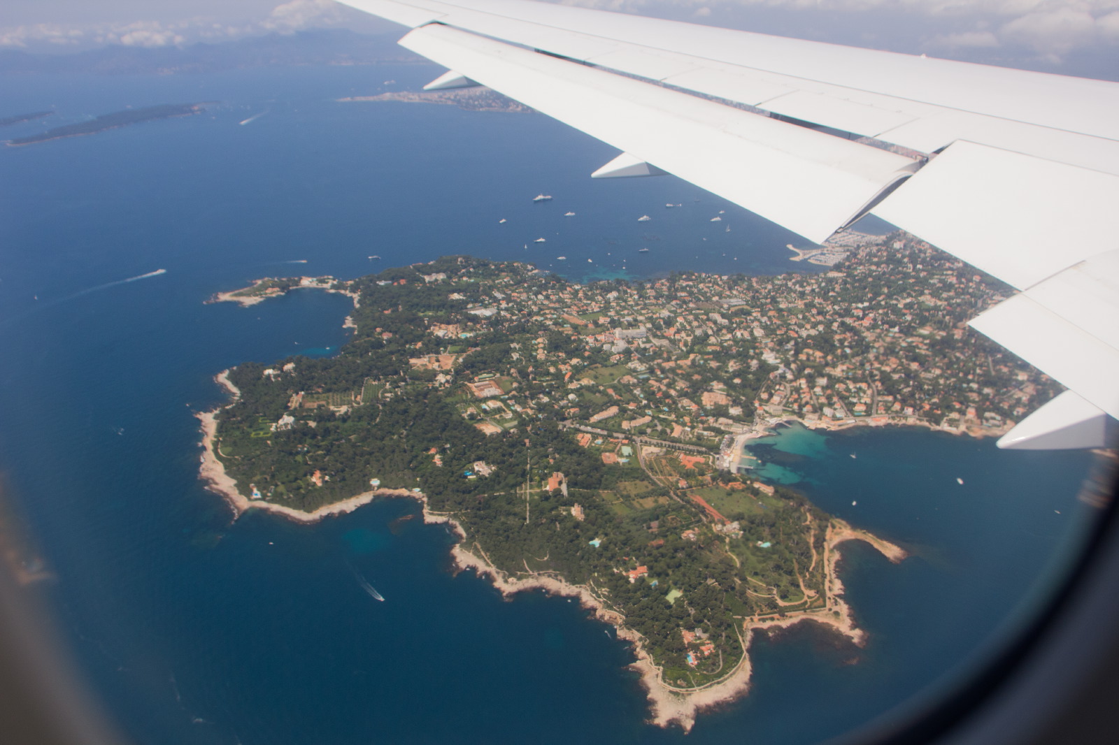 An airplane wing above the Mediterranean coastline on the journey to a destination wedding