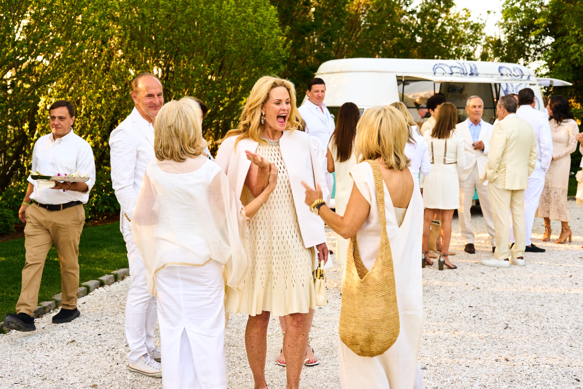Guests greeting one another with delighted expressions at a wedding weekend white party